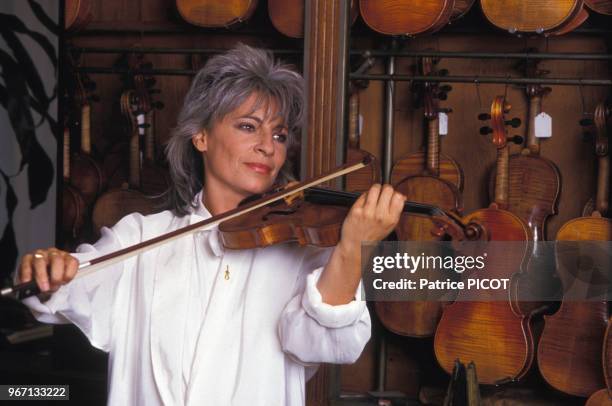 Catherine Lara essaie des violons chez un luthier à paris le 22 septembre 1986, France.