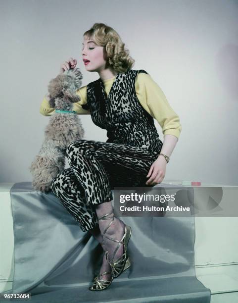 Model wearing an animal print trouser suit with gold sandals, circa 1955.