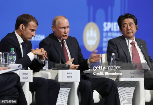 Vladimir Putin, Russia's president, center, speaks while Emmanuel Macron, France's president, left, and Shinzo Abe, Japan's prime minster, look on...