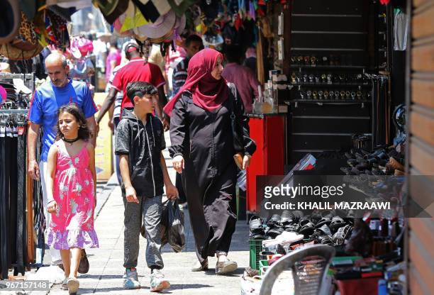 People stroll in a traditional market in downtown Amman on June 4, 2018. Jordan's King Abdullah has summoned the prime minister for a meeting that...