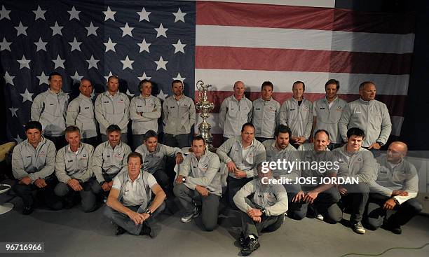 Oracle Racing team members pose with the trophy for the media in front of the Stars and Stripes during a press conference held in Valencia on...