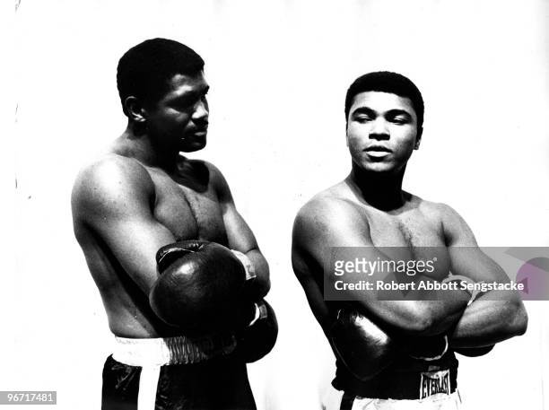 Boxers Ernie Terrell and Muhammad Ali stand next to each other in mock fighting poses during a pre-bout promotional event, probably in Houston, TX,...