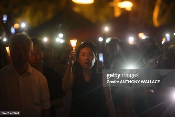 People hold candles during a vigil in Hong Kong on June 4 to mark the 29th anniversary of the 1989 Tiananmen crackdown in Beijing. - Crowds assembled...