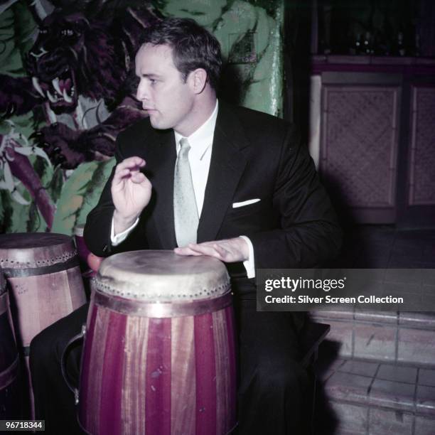 American actor Marlon Brando plays the conga drums at his home for an episode of the CBS program 'Person to Person', 1st April 1955.