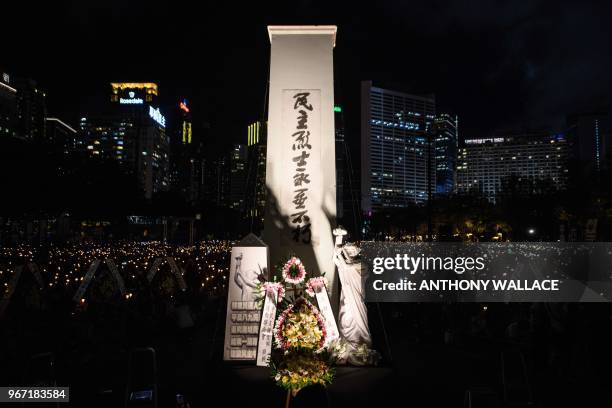 People hold candles near a cenotaph and Goddess of Democracy statue during a vigil in Hong Kong on June 4 to mark the 29th anniversary of the 1989...