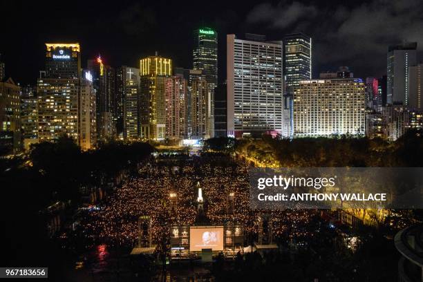 People hold candles during a vigil in Hong Kong on June 4 to mark the 29th anniversary of the 1989 Tiananmen crackdown in Beijing. - Crowds assembled...