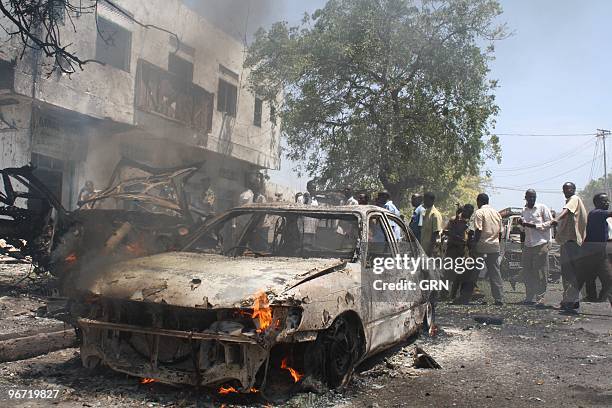 Onlookers view the wreckage of a suicide car bomb that targetted Somali government minister Sheikh Yusuf Siyad Indha Adde, in a government controlled...