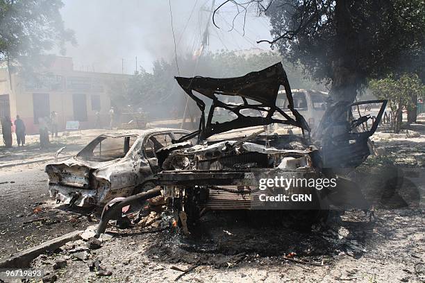 Onlookers view the wreckage of a suicide car bomb that targetted Somali government minister Sheikh Yusuf Siyad Indha Adde, in a government controlled...