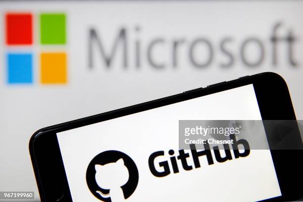 In this photo illustration the GitHub logo is seen on the screen of an iPhone in front of a computer screen showing a Microsoft logo on June 04, 2018...