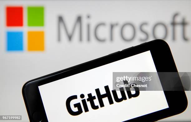 In this photo illustration the GitHub logo is seen on the screen of an iPhone in front of a computer screen showing a Microsoft logo on June 04, 2018...