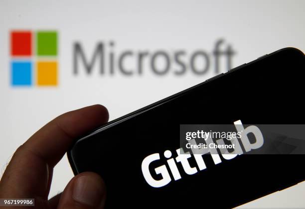 In this photo illustration the GitHub logo is seen on the screen of an iPhone in front of a computer screen showing a Microsoft logo on June 04, 2018...