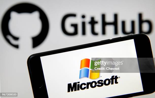 In this photo illustration the Microsoft logo is seen on the screen of an iPhone in front of a computer screen showing a GitHub logo on June 04, 2018...