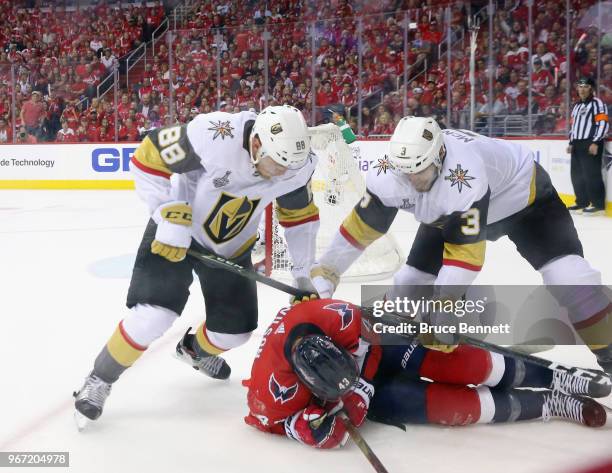 Nate Schmidt and Brayden McNabb of the Vegas Golden Knights combine to check Tom Wilson of the Washington Capitals during Game Three of the 2018 NHL...