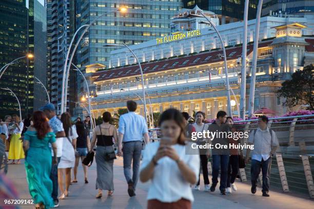 People walk on the Jubilee Bridge as the Fullerton Hotel stands in the background on June 4, 2018 in Singapore. U.S. President Donald Trump announced...