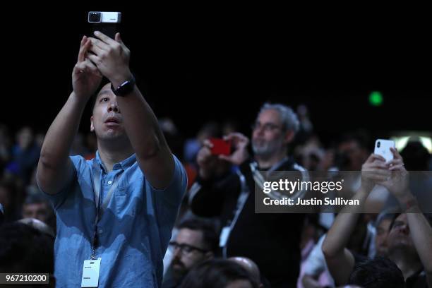 Attendees take pictures before the start of the opening keynote during the 2018 Apple Worldwide Developer Conference at the San Jose Convention...