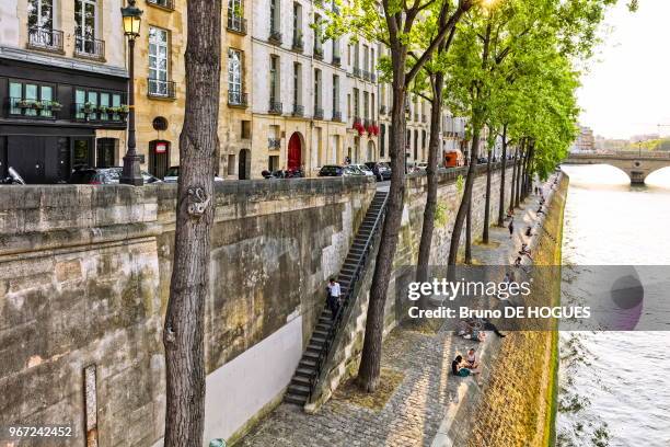 Des gens assis sur le quai de la Corse de l'Île Saint-Louis, 20 juin 2017, Paris, France.