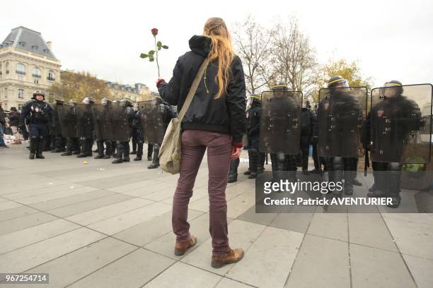 Manifestante avec une rose et police anti émeute lors de la manifestation pour defendre le climat et rappeler l'etat d'urgence climatique, place de...