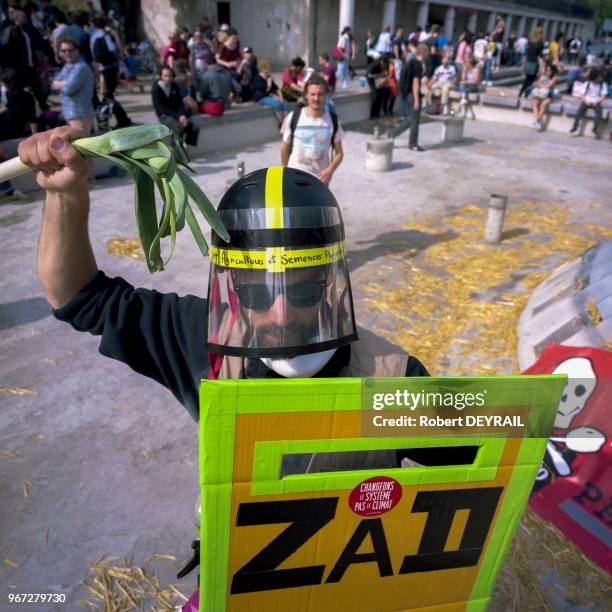 Manifestant portant un casque de CRS, un poireau faisant office de matraque et une pancarte en guise de bouclier anti-émeute avec une inscription...