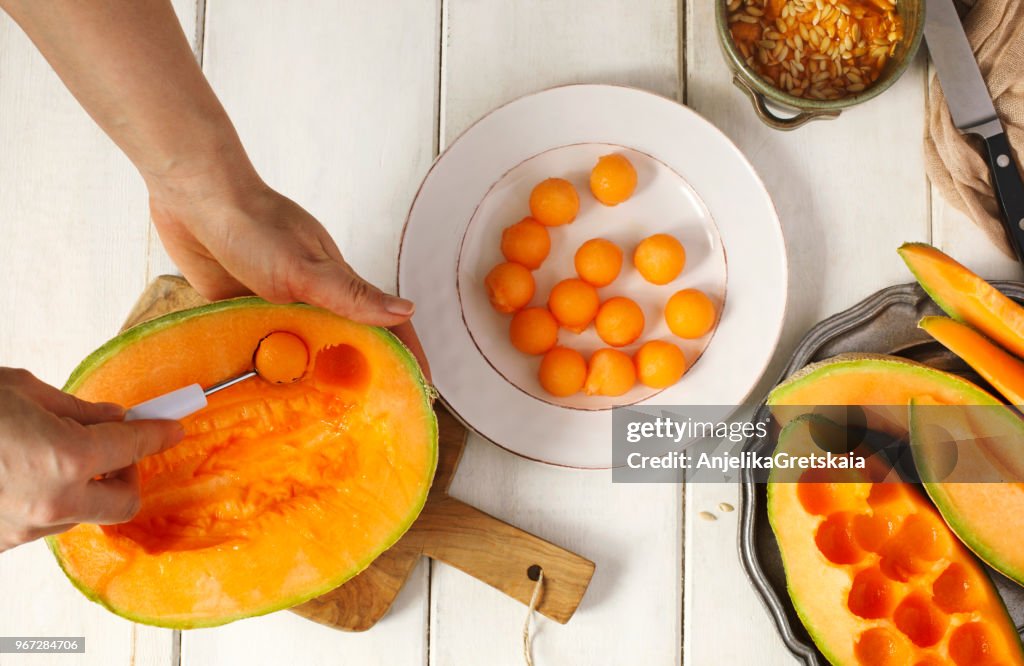Woman preparing melon balls with a cantaloupe melon