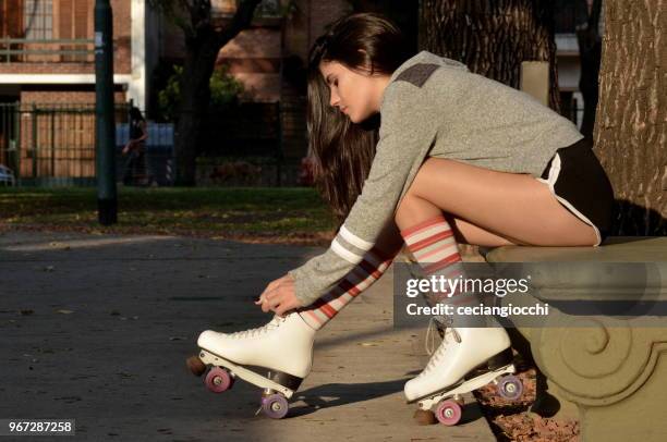 teenage girl tying shoe laces on her roller skates - knee length photos et images de collection