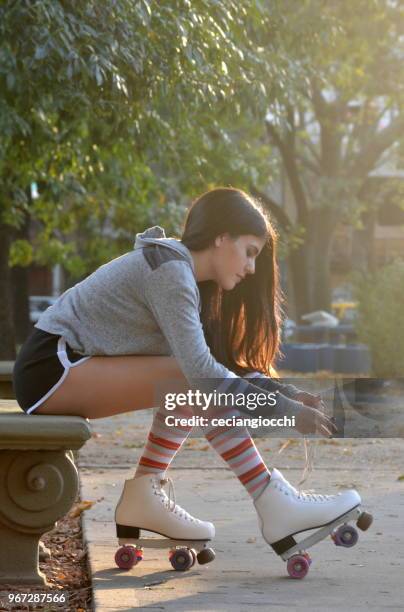 girl tying the shoelaces on her roller skates - roller skating in park stock pictures, royalty-free photos & images