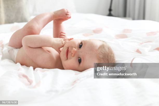 baby girl lying on a bed - vida de bebé fotografías e imágenes de stock