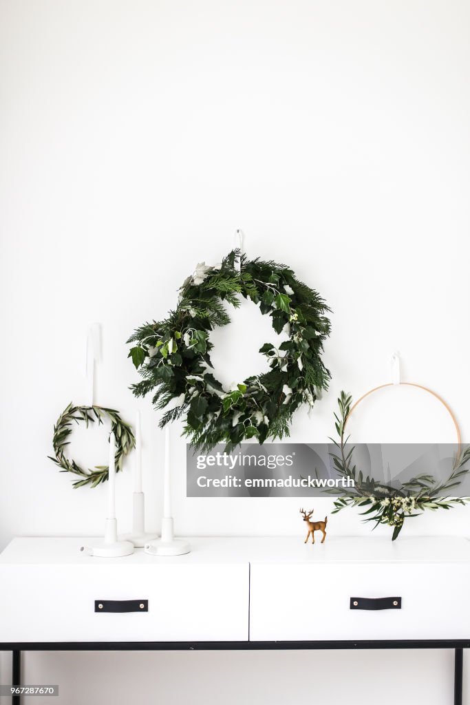 Wreaths hanging on a wall by a sideboard