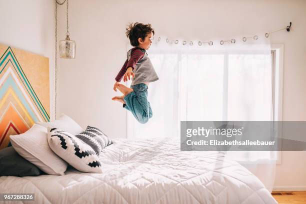 boy jumping on a bed - children jumping bed stock-fotos und bilder