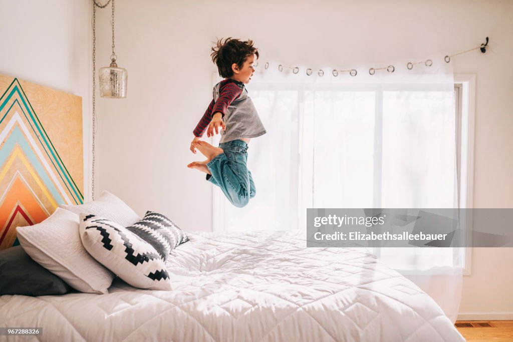 Boy jumping on a bed