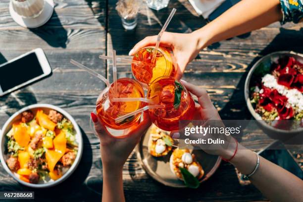 overhead view of three women making a celebratory toast with spritz cocktails - summer refreshment stock pictures, royalty-free photos & images