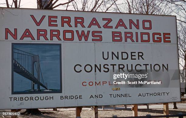 New York City - A large sign is erected in Brooklyn, New York as construction of the Verrazano-Narrows Bridge begins.