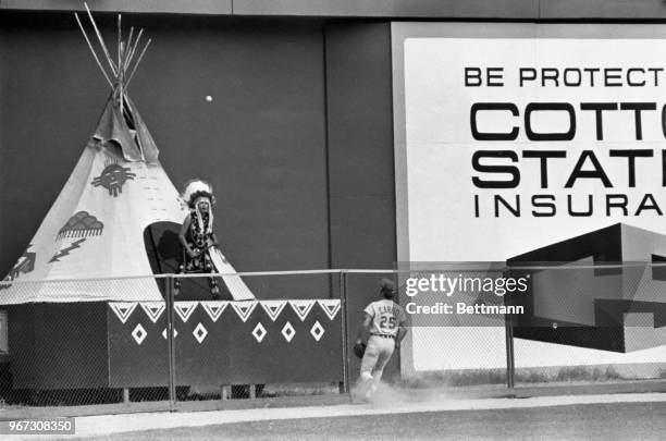 Cincinnati Reds outfielder Bernie Carbo joins Atlanta Braves mascot Chief Hocahoma in watching the ball bounce over the fence for a ground rule...