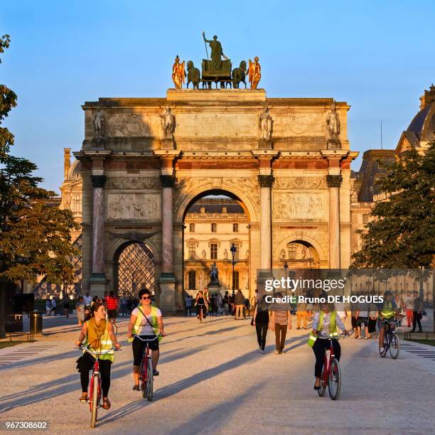 Des cyclistes devant l'Arc de Triomphe du Carrousel au coucher de soleil, 17 juin 2017, Paris, France.