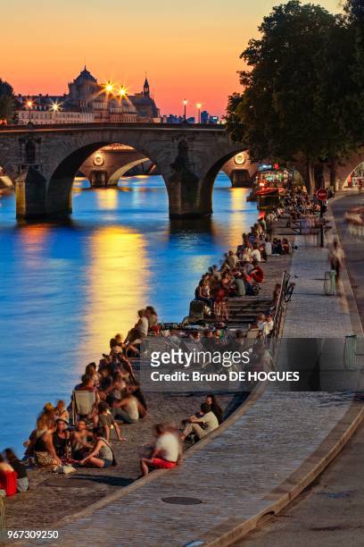 Groupes de gens assis au bord des quais de Seine par forte chaleur à la tombée de la nuit près des Ponts Marie et Louis-Philippe, le 18 juin 2017 à...