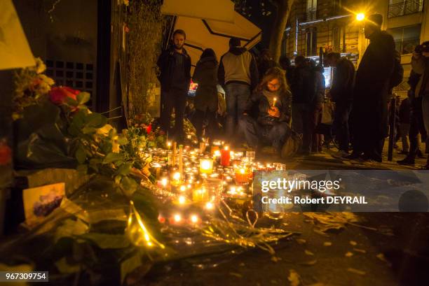 De nombreuses personnes viennent se recueillir et apporter fleurs et bougies devant le rideau baissé du bar 'La belle équipe', le 14 Novembre 2015 à...