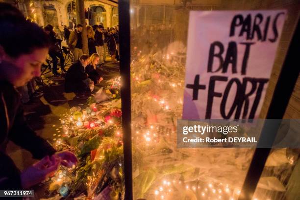 De nombreuses personnes viennent se recueillir et apporter fleurs et bougies devant le rideau baissé du bar 'La belle équipe', le 14 Novembre 2015 à...