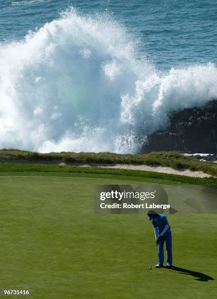 Ryo Ishikawa of Japan makes a putt on the seventh green as waves come crashing on the rocks during the third round of the AT&T Pebble Beach National...