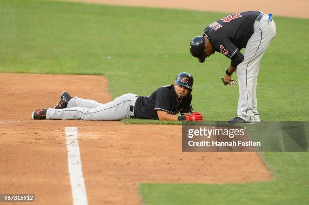 First base coach Sandy Alomar Jr. #15 of the Cleveland Indians speaks with Melky Cabrera after he was tagged out by the Minnesota Twins during the...