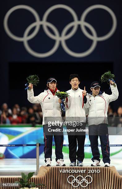 Keiichiro Nagashima of Japan celebrates winning silver, Mo Tae-Bum of South Korea gold and Joji Kato of Japan bronze during the flower ceremony for...