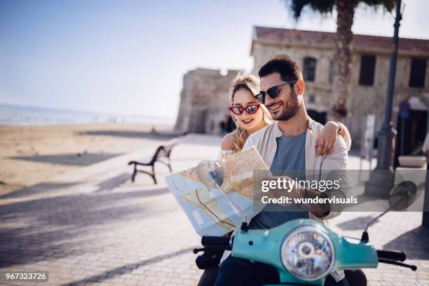 touristen-paar mit retro-scooter lesen karte auf insel im mittelmeer - motorcycle travel stock-fotos und bilder