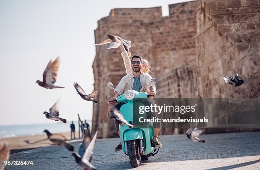 Joven pareja teniendo diversión scooter de montar a caballo en el casco antiguo europeo Joven pareja teniendo diversión scooter de montar a caballo en el casco antiguo europeo