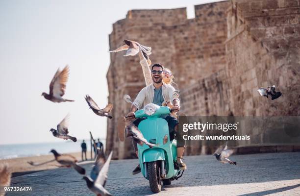 joven pareja teniendo diversión scooter de montar a caballo en el casco antiguo europeo - viajes fotografías e imágenes de stock