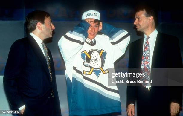 Paul Kariya tries on his hat and jersey after being drafted 4th overall in the 1993 NHL Entry Draft as he stands on stage with NHL Commisioner Gary...