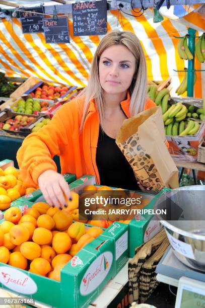 Vendeuse de primeurs servant des abricots au marché Edgard Quinet, 17 juin 2017, Paris, France.