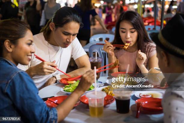 freunde genießen einen lokalen nachtmarkt - malaysian culture stock-fotos und bilder