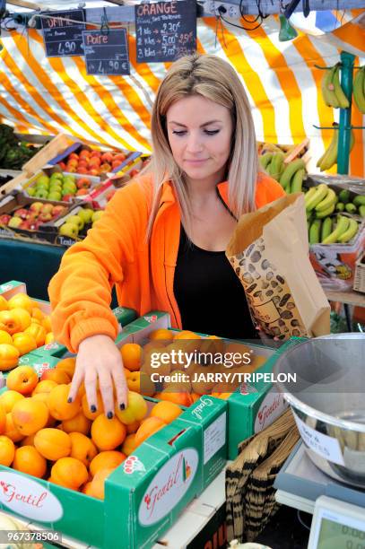 Vendeuse de primeurs servant des abricots au marché Edgard Quinet, 17 juin 2017, Paris, France.