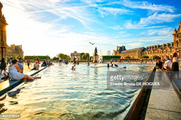 Des enfants se baignant dans le bassin de la Pyramide du Louvre par une forte chaleur, 25 aout 2016, Paris, France.