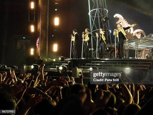 Jason Orange, Gary Barlow, Mark Owen and Howard Donald of Take That are cheered on by a waving crowd, while performing on stage on the final date of...