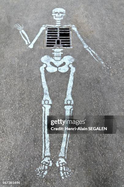 Balade a Paris, rue des Chartreux. Oeuvre de Street Art, non signee, autour d'une bouche d'egout sur un trottoir.