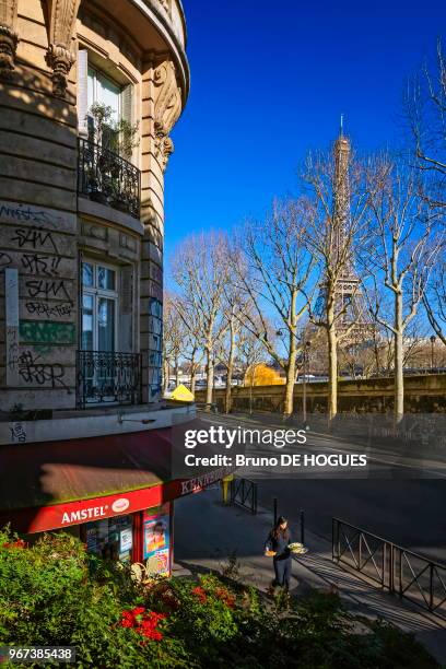 Une femme portant des assiettes devant le bistrot de l'Avenue du Président Kennedy à Paris, France.